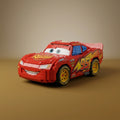 Assembled brick-built Lightning McQueen race car model on a tan backdrop