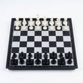 Folding magnetic chess board set up with all 32 pieces on white background